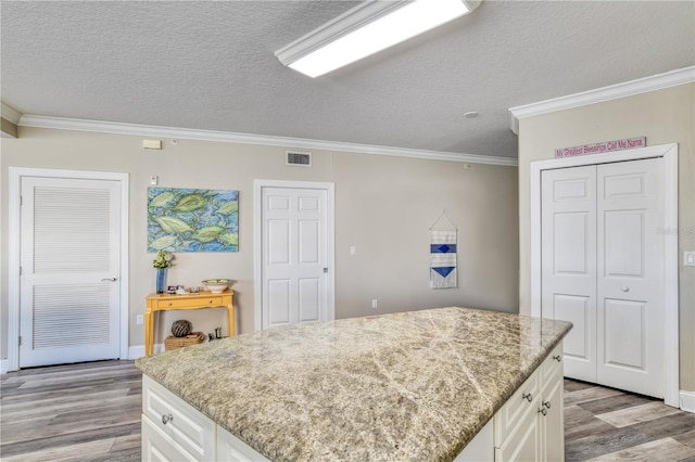 kitchen with a textured ceiling, white cabinetry, and ornamental molding