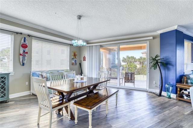 dining area with hardwood / wood-style flooring, plenty of natural light, a textured ceiling, and ornamental molding