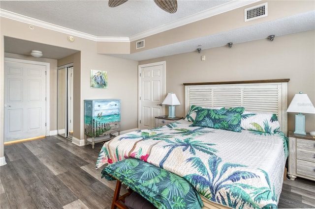 bedroom with a textured ceiling, dark wood-type flooring, a closet, ceiling fan, and crown molding