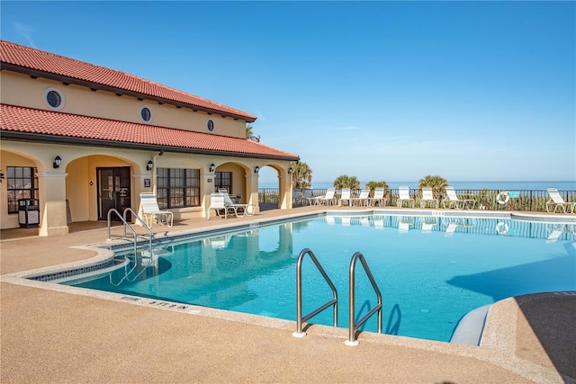 view of swimming pool with a water view and a patio area