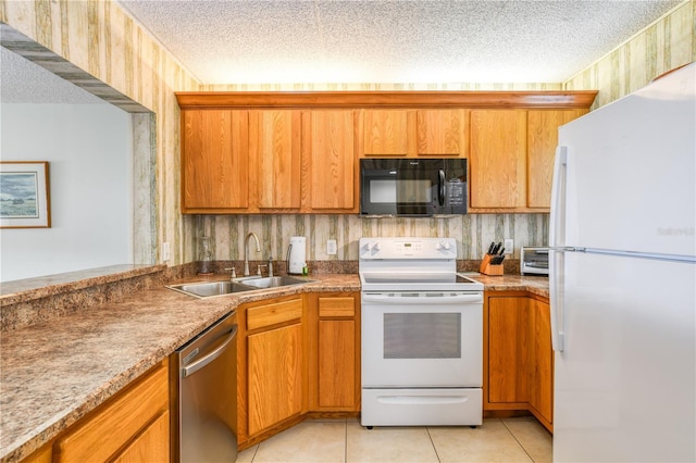 kitchen with a textured ceiling, light tile patterned floors, sink, and white appliances