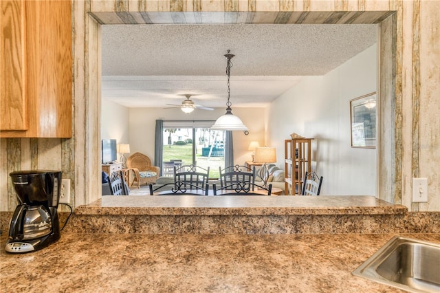 kitchen with hanging light fixtures, ceiling fan, and a textured ceiling