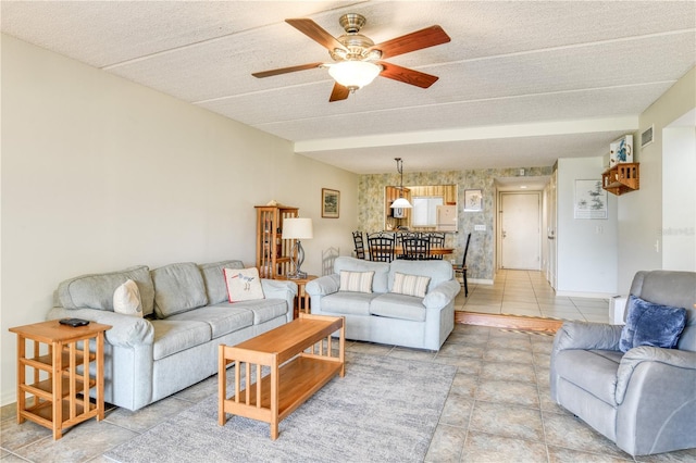 living room featuring ceiling fan, light tile patterned floors, and a textured ceiling