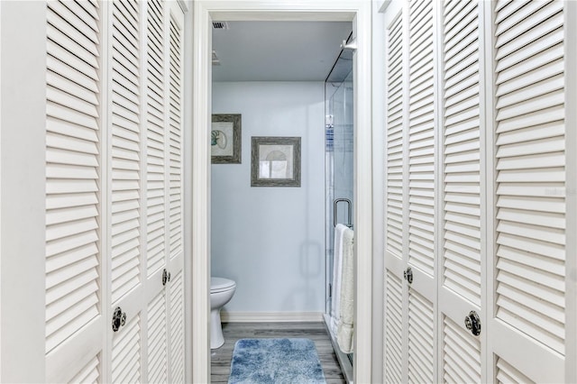 bathroom featuring toilet, wood-type flooring, and an enclosed shower