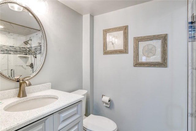 bathroom featuring a shower with shower door, vanity, and toilet