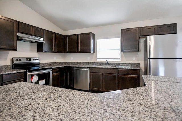 kitchen featuring appliances with stainless steel finishes, sink, vaulted ceiling, light stone counters, and dark brown cabinets