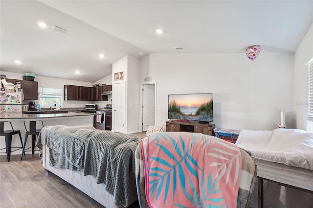 living area with recessed lighting, visible vents, vaulted ceiling, and wood finished floors