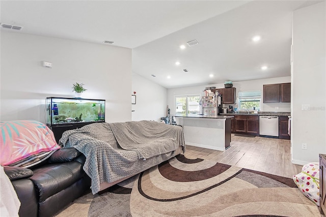 living area featuring light wood-style floors, visible vents, and vaulted ceiling