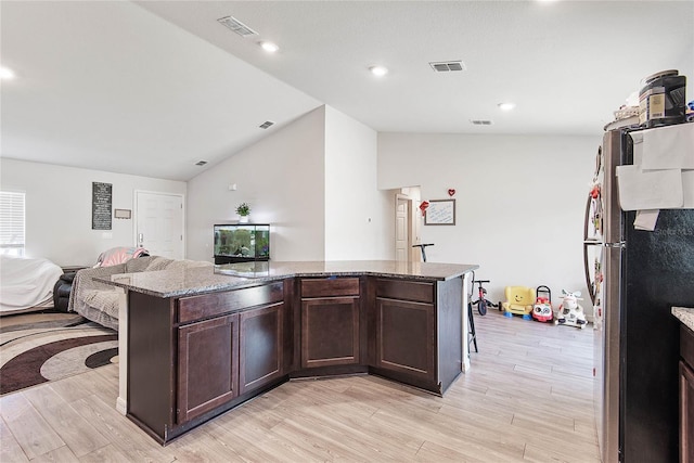 kitchen with dark brown cabinetry, a center island, visible vents, and freestanding refrigerator