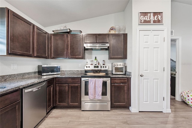 kitchen with stainless steel appliances, vaulted ceiling, dark brown cabinetry, light wood-type flooring, and under cabinet range hood