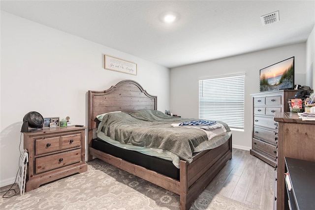 bedroom featuring baseboards, visible vents, and light wood finished floors