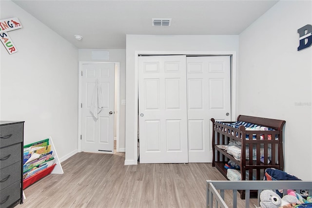 bedroom with light wood-style flooring, a closet, visible vents, and baseboards