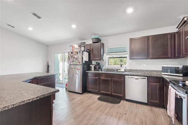 kitchen featuring visible vents, dark countertops, light wood-style flooring, appliances with stainless steel finishes, and a sink