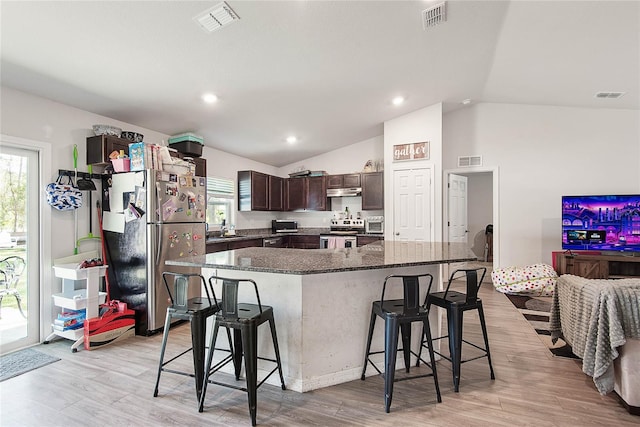 kitchen with dark brown cabinets, appliances with stainless steel finishes, a kitchen bar, and visible vents