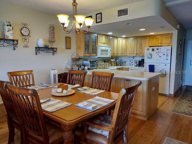 dining room with light hardwood / wood-style flooring and an inviting chandelier