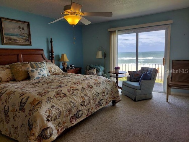 carpeted bedroom with a textured ceiling, access to exterior, a water view, and ceiling fan