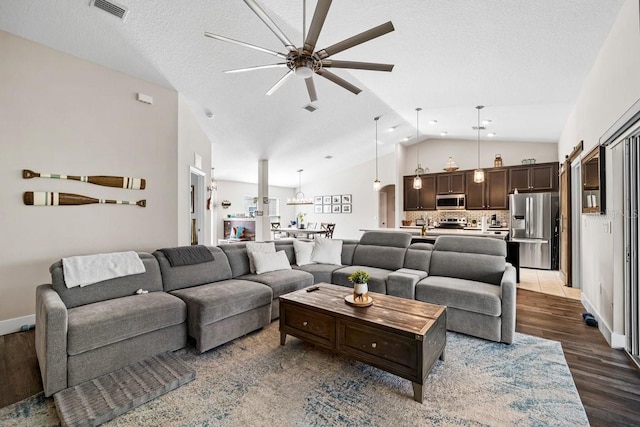 living room with vaulted ceiling, ceiling fan, a textured ceiling, and dark hardwood / wood-style flooring