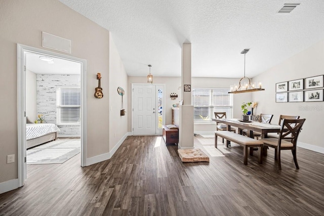 foyer entrance featuring an inviting chandelier, dark hardwood / wood-style flooring, vaulted ceiling, and a textured ceiling