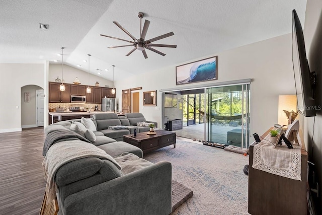 living room with lofted ceiling, a textured ceiling, dark wood-type flooring, and ceiling fan