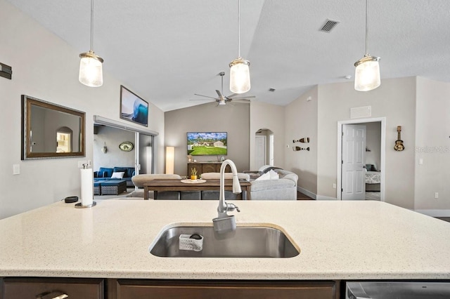 kitchen with hanging light fixtures, lofted ceiling, sink, and a textured ceiling