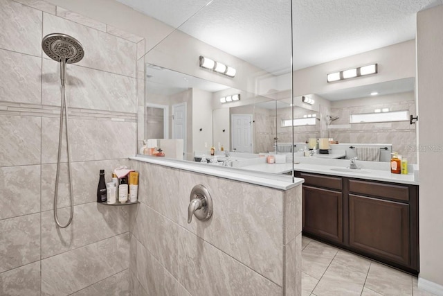 bathroom featuring vanity, a tile shower, and a textured ceiling