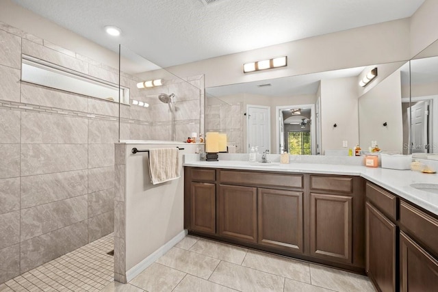 bathroom with tiled shower, vanity, tile patterned flooring, and a textured ceiling