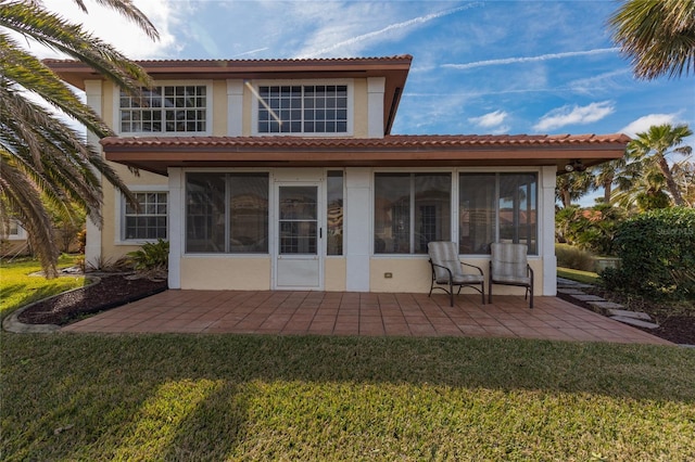 rear view of property featuring a yard, a patio area, and a sunroom