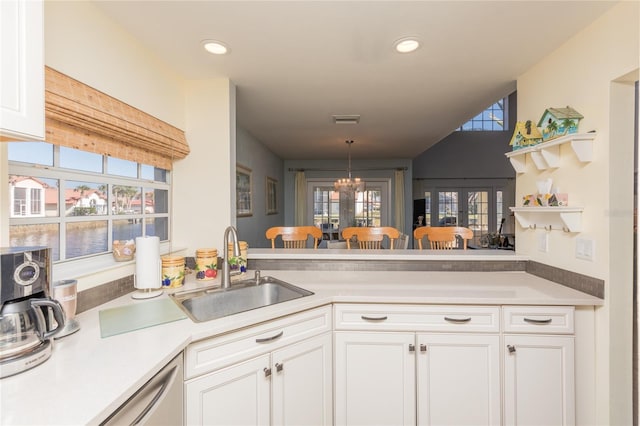 kitchen with kitchen peninsula, sink, hanging light fixtures, and white cabinets