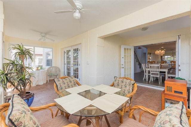 tiled dining space featuring ceiling fan with notable chandelier, a wealth of natural light, and french doors