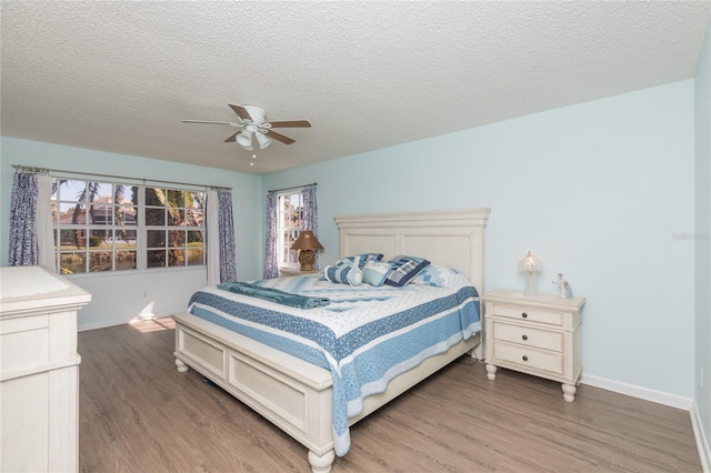 bedroom with multiple windows, ceiling fan, hardwood / wood-style floors, and a textured ceiling