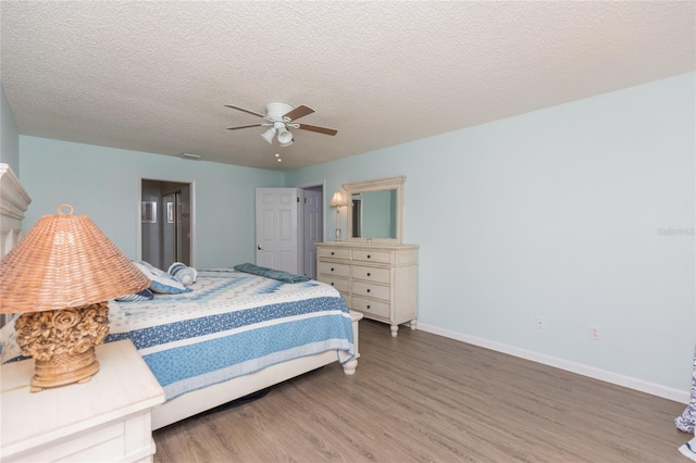 bedroom with wood-type flooring, a textured ceiling, and ceiling fan