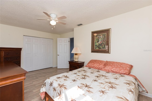 bedroom featuring light wood-type flooring, a textured ceiling, ceiling fan, and a closet