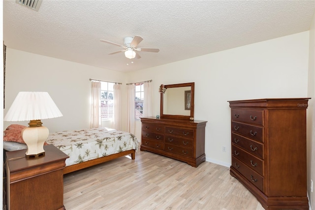 bedroom with ceiling fan, a textured ceiling, and light wood-type flooring