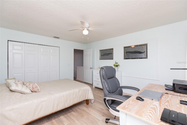 bedroom featuring ceiling fan, a textured ceiling, a closet, and light wood-type flooring