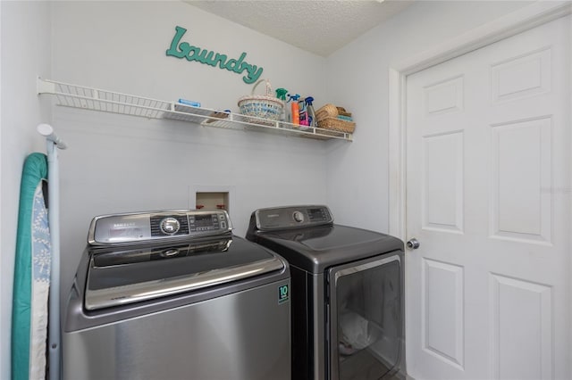 clothes washing area with washing machine and dryer and a textured ceiling