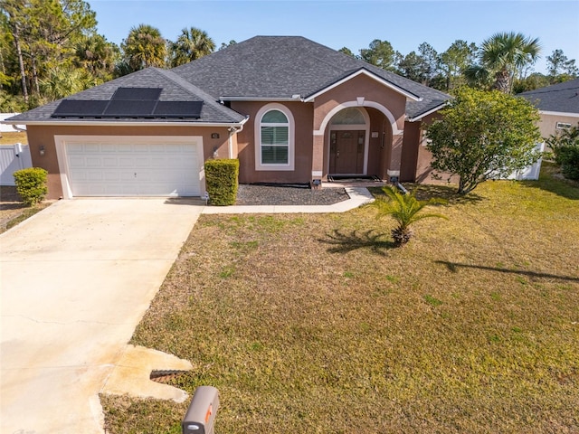 view of front of home with a garage, a front yard, and solar panels