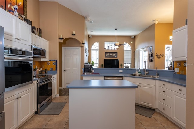 kitchen featuring a kitchen island, sink, white cabinets, kitchen peninsula, and stainless steel appliances