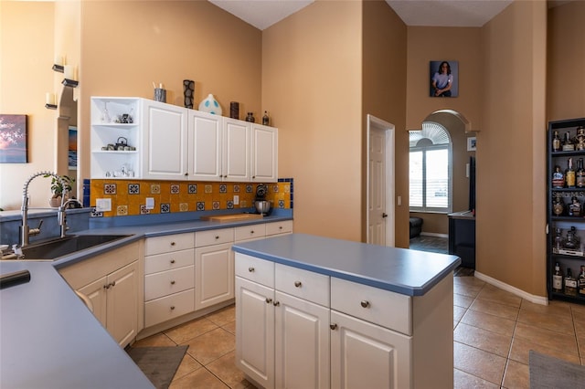 kitchen featuring white cabinetry, light tile patterned flooring, sink, and backsplash