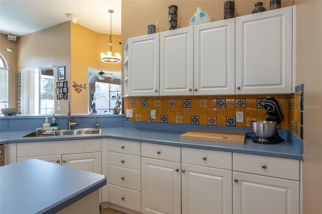 kitchen with sink, hanging light fixtures, tasteful backsplash, white cabinets, and a chandelier