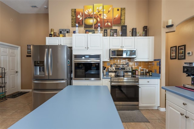 kitchen featuring white cabinetry, light tile patterned floors, backsplash, and appliances with stainless steel finishes