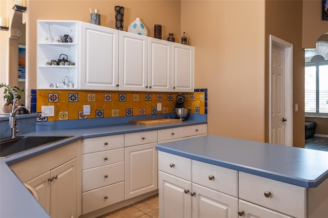 kitchen with white cabinetry, light tile patterned floors, sink, and backsplash