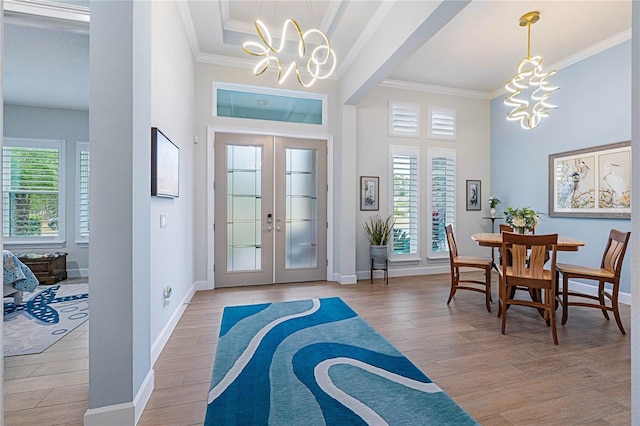 foyer featuring french doors, a healthy amount of sunlight, light wood-type flooring, and a notable chandelier