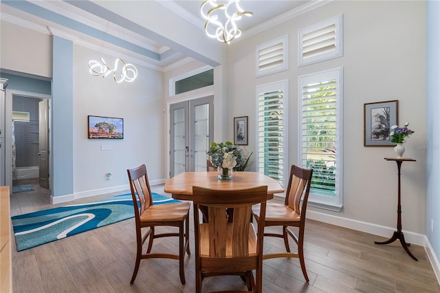 dining room featuring hardwood / wood-style flooring, ornamental molding, a chandelier, and french doors