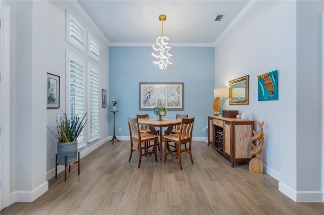 dining room with a wealth of natural light, ornamental molding, light hardwood / wood-style floors, and a chandelier