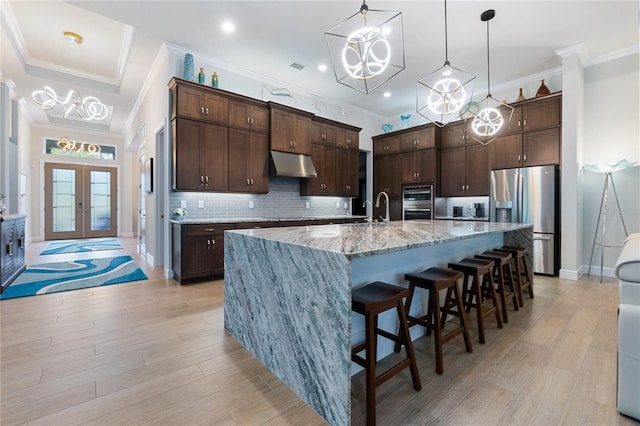 kitchen with french doors, a spacious island, dark brown cabinetry, and stainless steel fridge