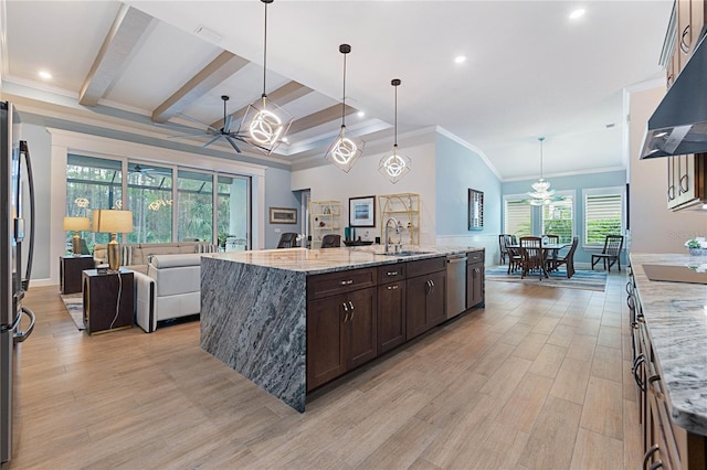 kitchen with hanging light fixtures, light stone countertops, sink, and a spacious island