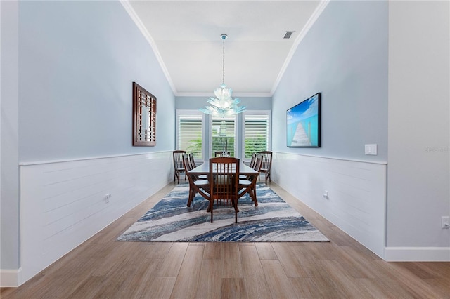 dining space featuring crown molding, an inviting chandelier, vaulted ceiling, and hardwood / wood-style floors