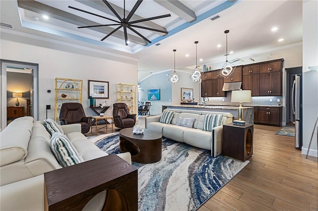 living room with a tray ceiling, ornamental molding, beamed ceiling, and light wood-type flooring