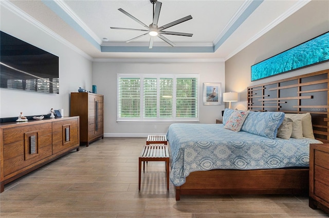 bedroom featuring crown molding, a tray ceiling, ceiling fan, and light hardwood / wood-style floors