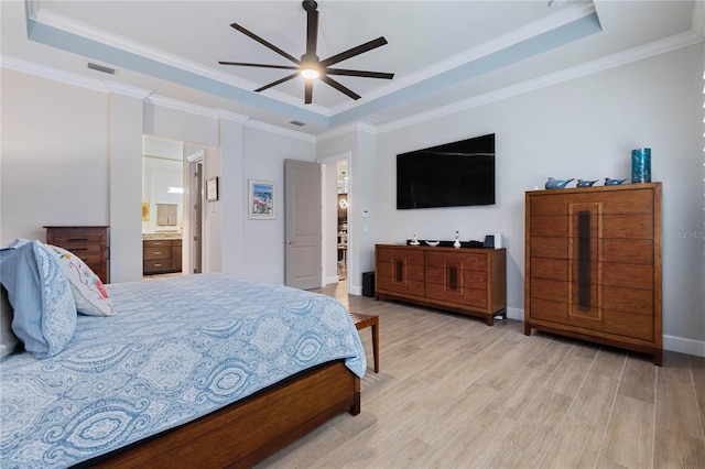 bedroom featuring crown molding, ensuite bath, ceiling fan, and a tray ceiling